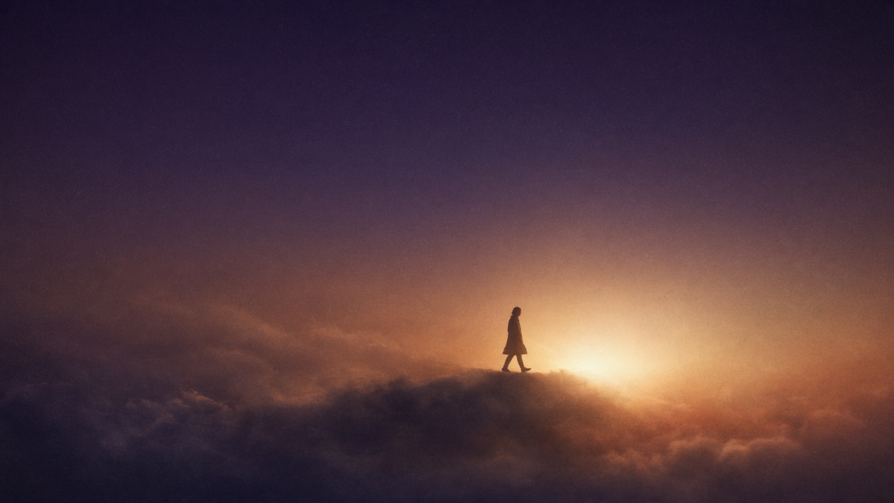 A silhouetted figure crossing through gold light in open indigo space